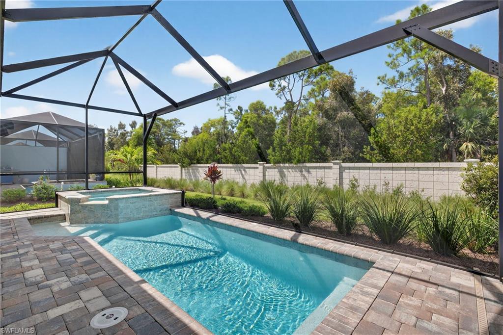 View of swimming pool with a patio, a fenced backyard, a lanai, a pool with connected hot tub, and a sunroom