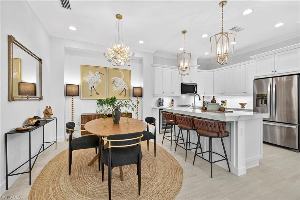 Dining room with a chandelier, ornamental molding, recessed lighting, and light wood-style flooring