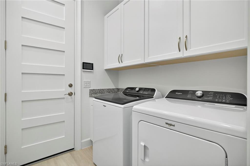 Washroom featuring cabinet space, washer and dryer, and light wood-type flooring
