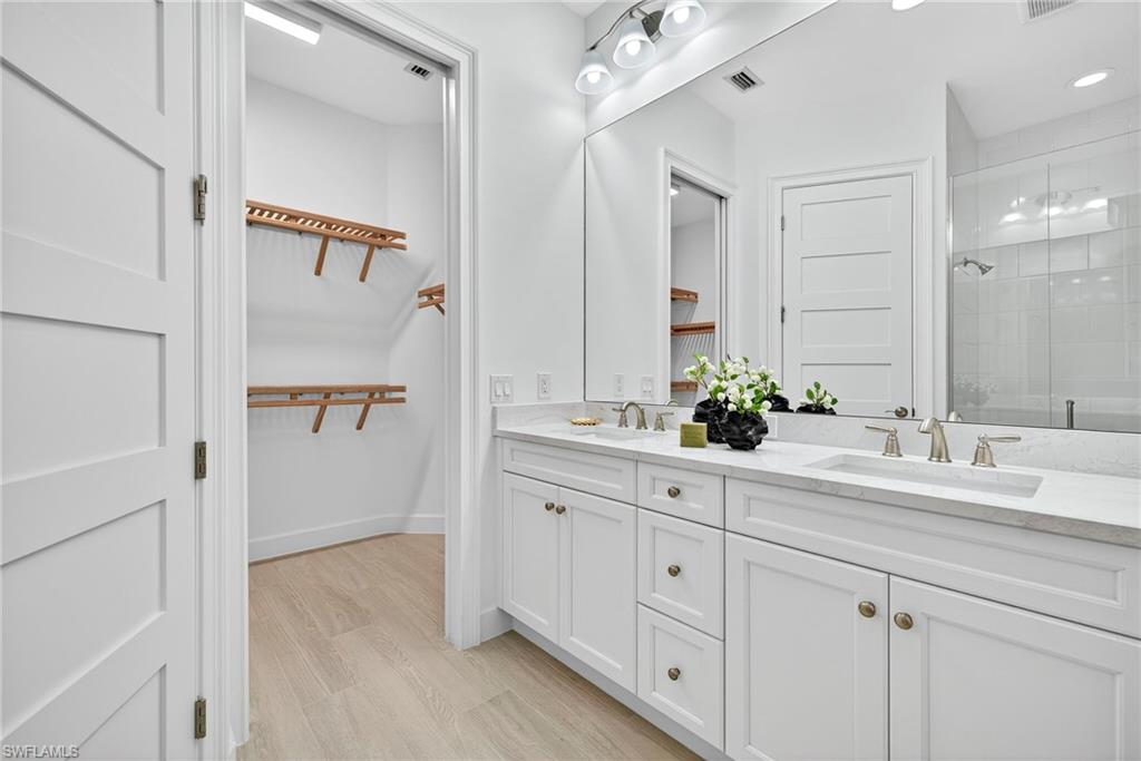 Full bathroom featuring double vanity, a stall shower, and light wood-type flooring