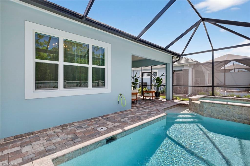 View of pool with a sunroom, glass enclosure, a patio area, and a pool with connected hot tub