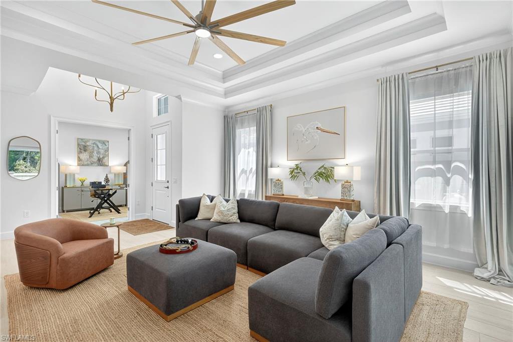 Living room with a tray ceiling, ornamental molding, a ceiling fan, wood finished floors, and recessed lighting