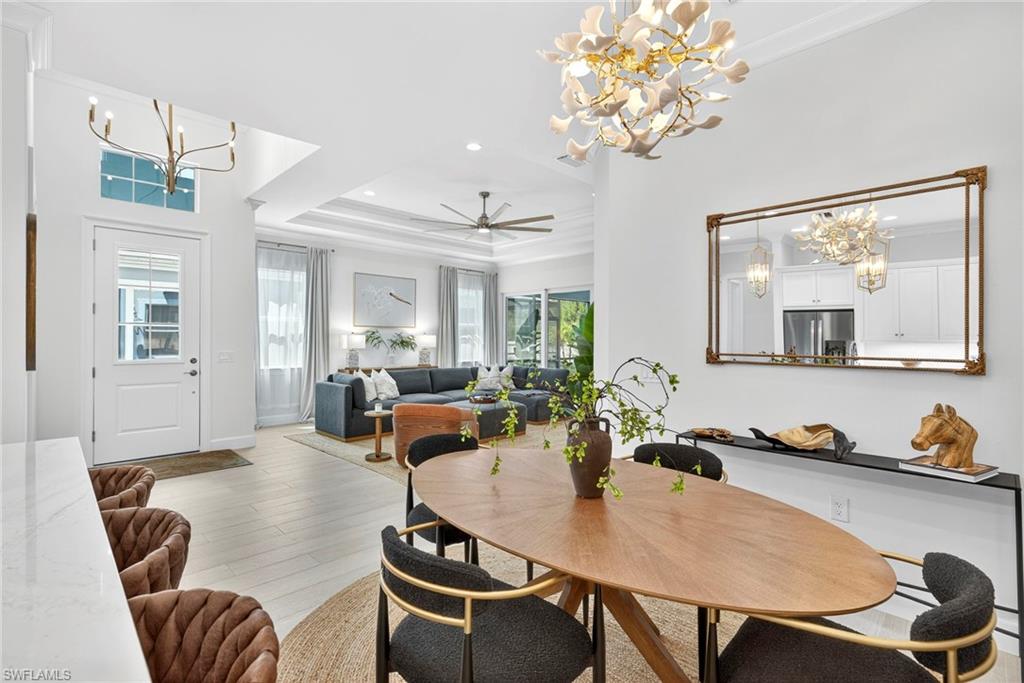 Dining space featuring a chandelier, a tray ceiling, wood finished floors, ornamental molding, and recessed lighting
