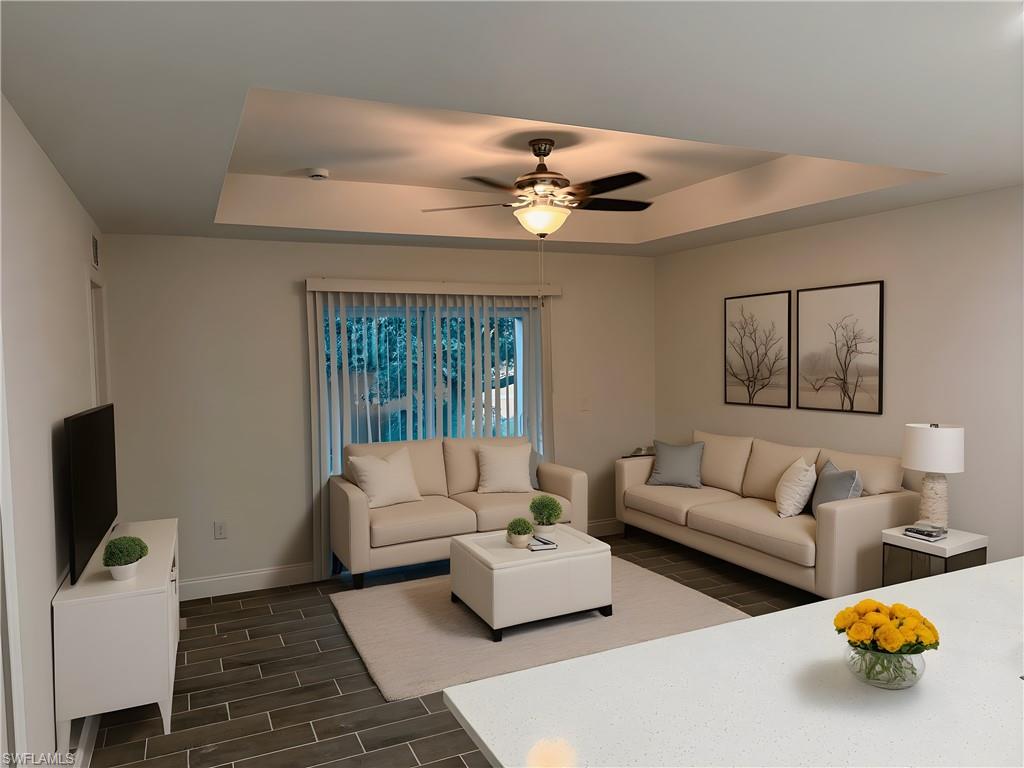 Living room featuring a tray ceiling, wood tiled floors, and a ceiling fan