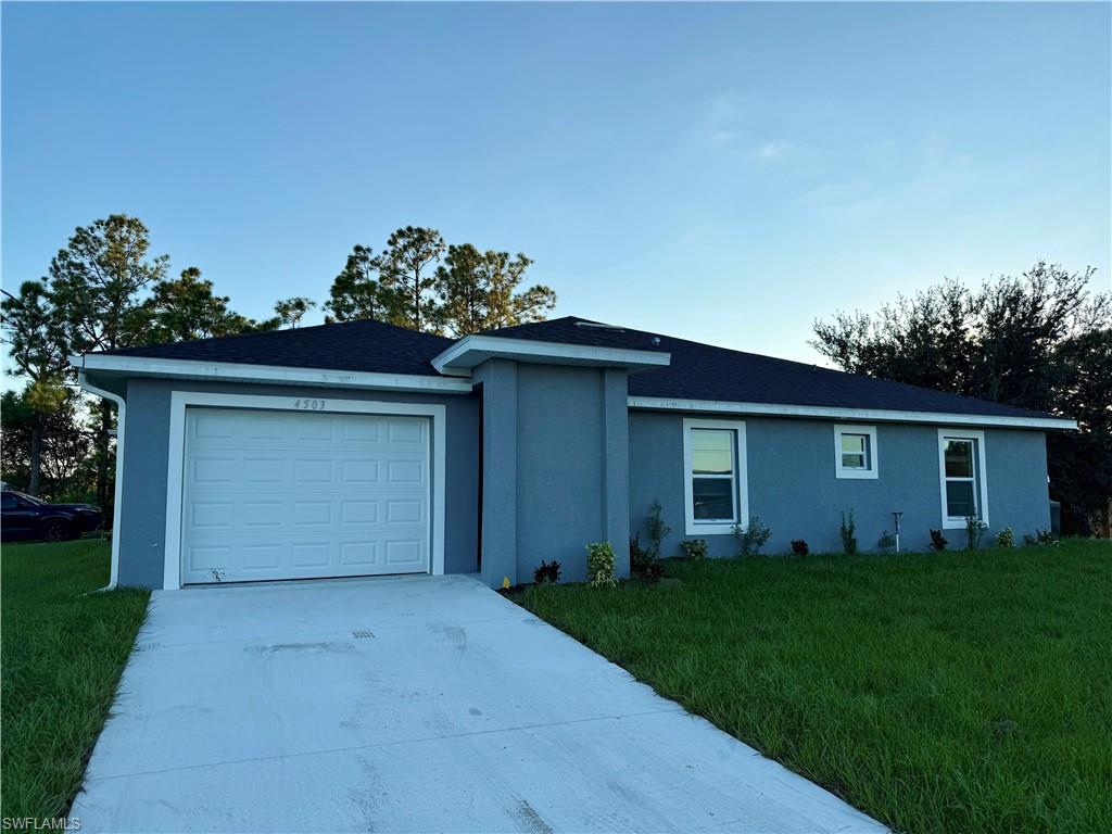 Ranch-style home featuring concrete driveway, a front lawn, and stucco siding
