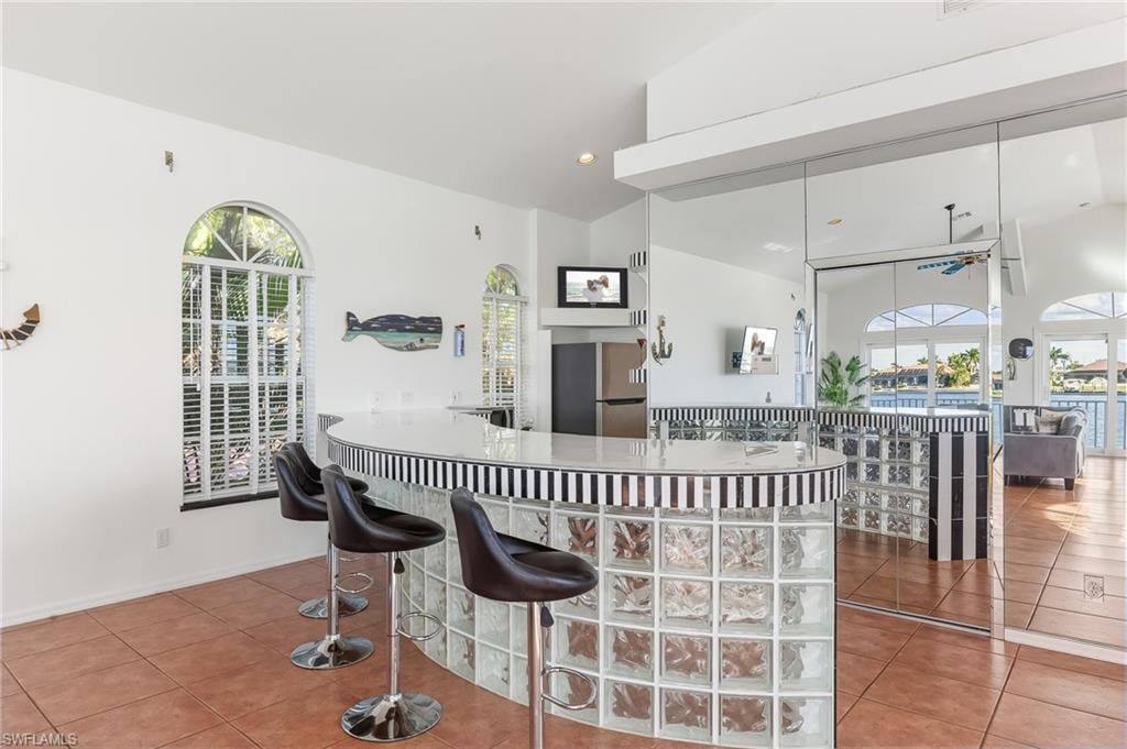 Kitchen featuring freestanding refrigerator, vaulted ceiling, recessed lighting, a kitchen breakfast bar, and a ceiling fan