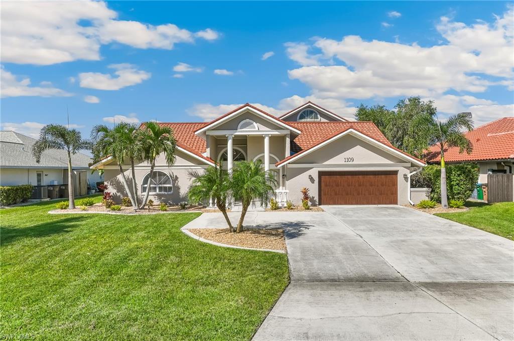 View of front of home with a front lawn, driveway, and stucco siding