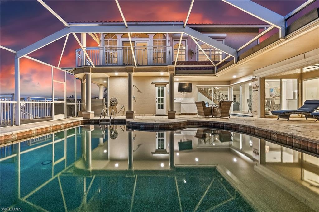 Outdoor pool featuring glass enclosure, a patio area, and a balcony