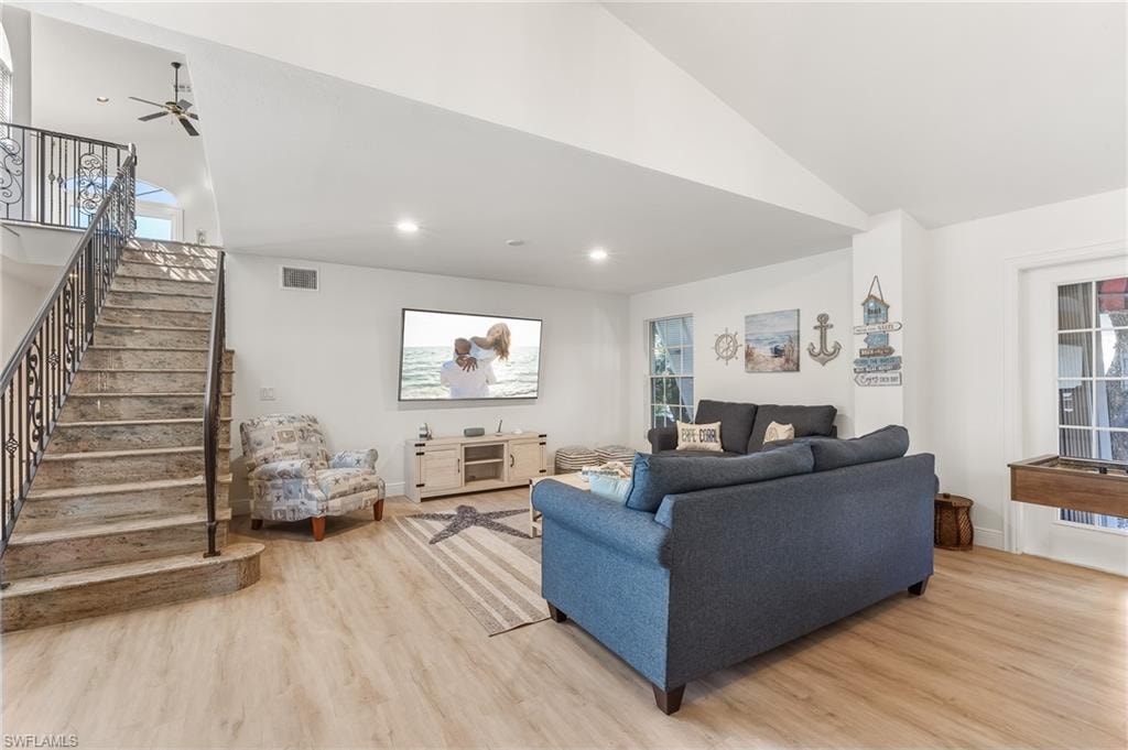 Living room featuring light wood-type flooring, recessed lighting, stairway, and high vaulted ceiling