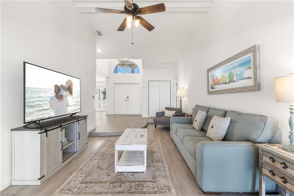 Living room with high vaulted ceiling, light wood-style floors, and a ceiling fan