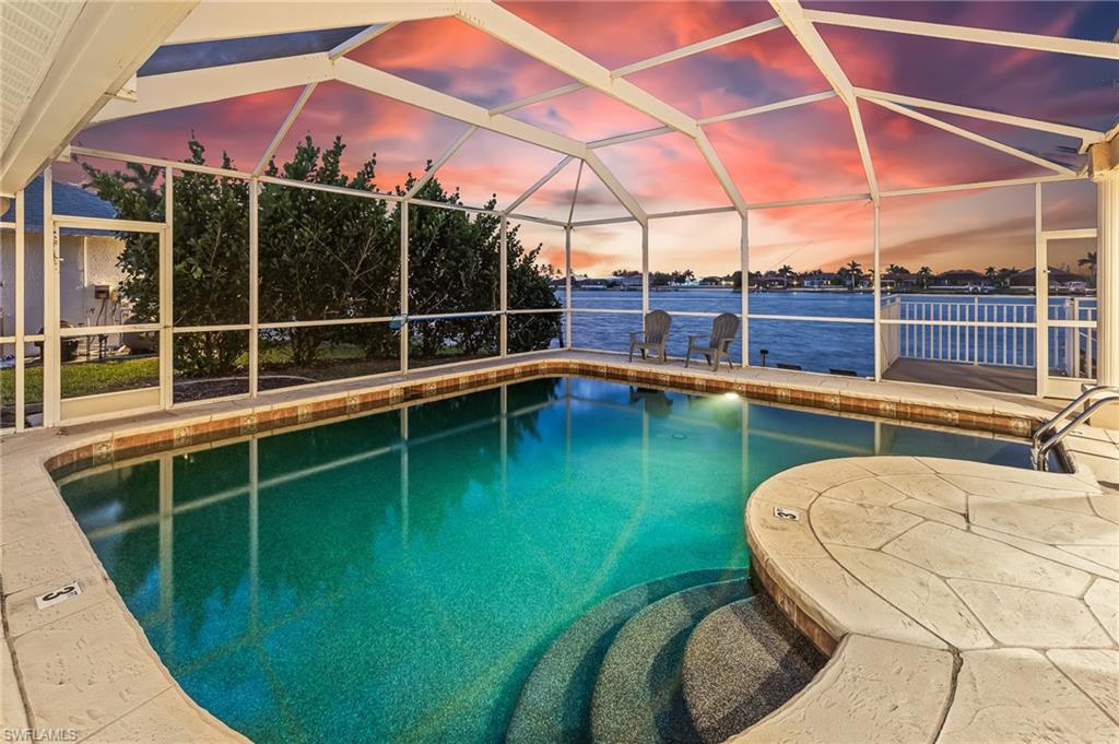 Swimming pool with glass enclosure, a sunroom, and a water view
