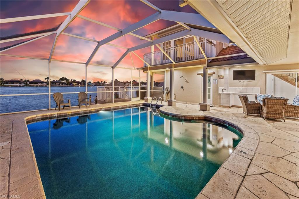 Outdoor pool featuring glass enclosure, a patio, a balcony, and a water view
