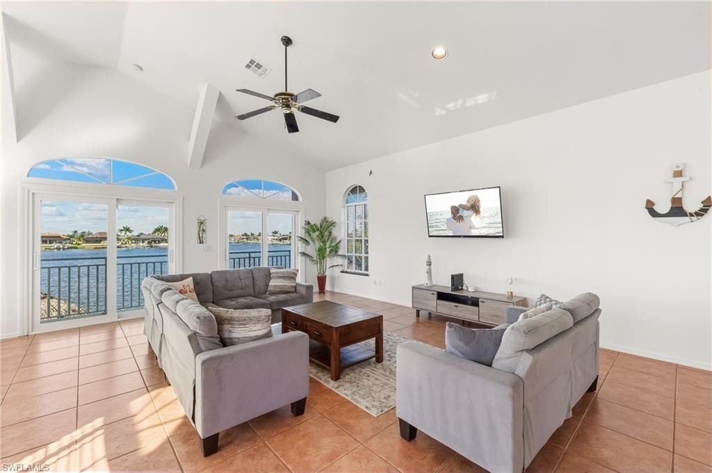 Living area with light tile patterned floors, high vaulted ceiling, a water view, recessed lighting, and ceiling fan