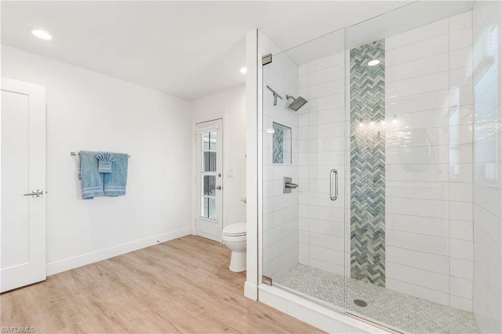 Full bath featuring light wood finished floors, a stall shower, and recessed lighting