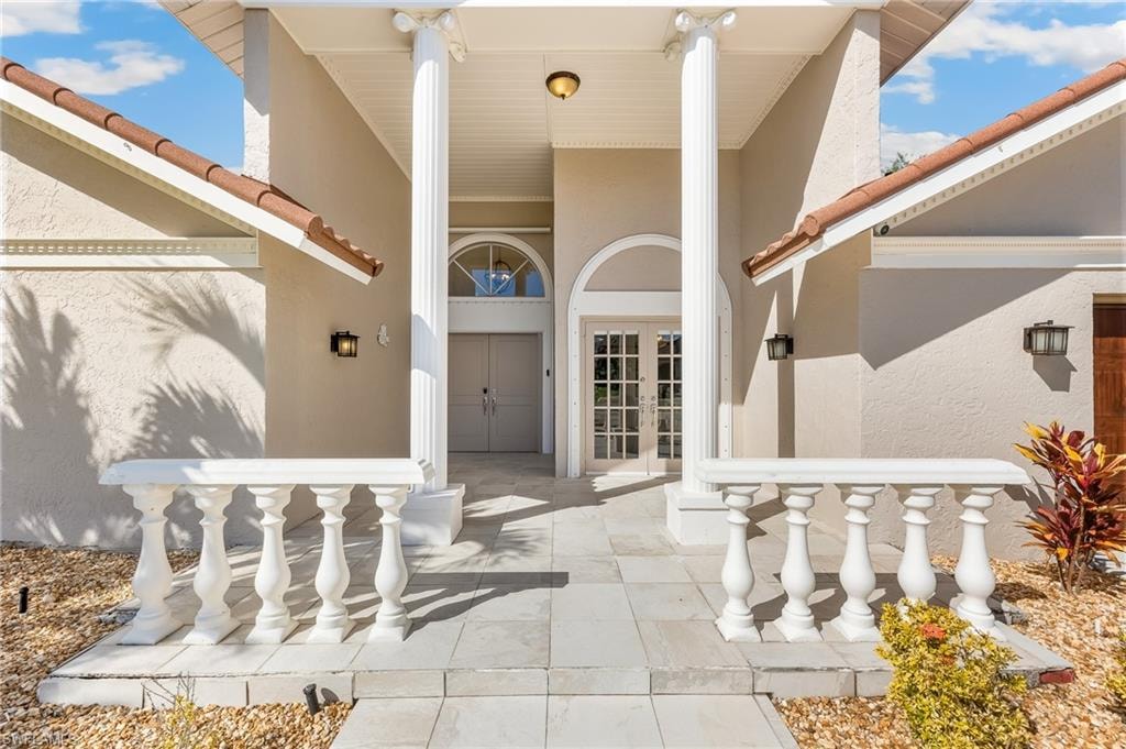 Entrance to property with a tiled roof, stucco siding, and french doors
