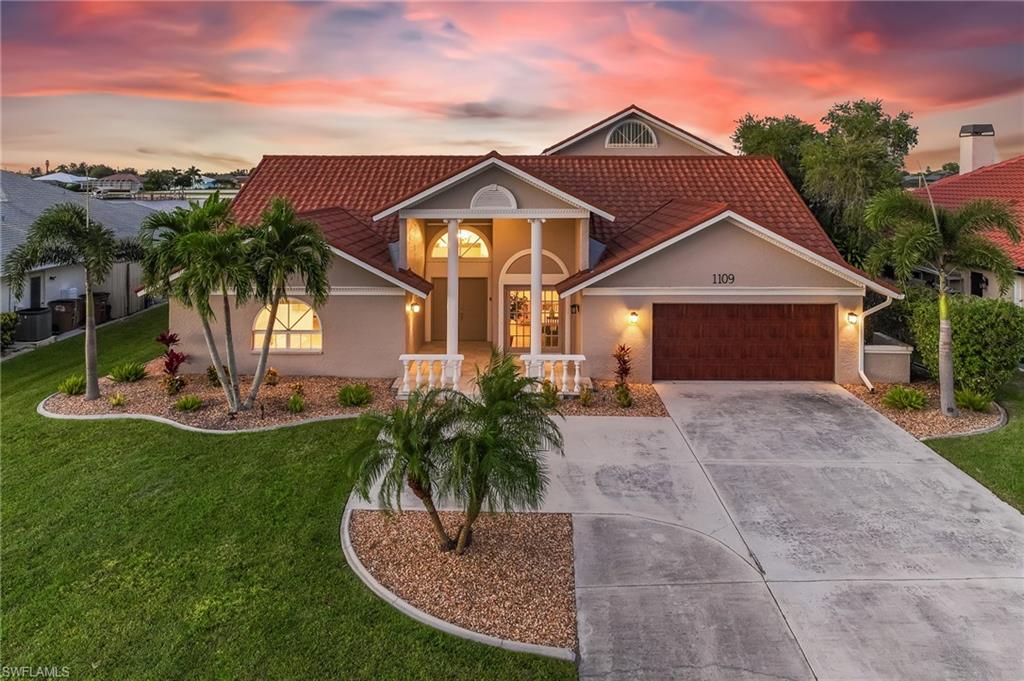 View of front of house featuring concrete driveway, an attached garage, a tile roof, and stucco siding
