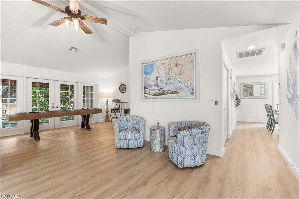 Living area with french doors, light wood finished floors, beam ceiling, high vaulted ceiling, and a ceiling fan