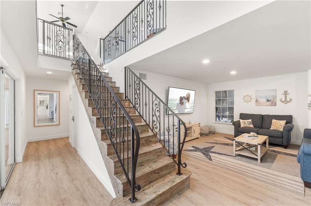 Staircase with wood finished floors, a towering ceiling, recessed lighting, and a ceiling fan