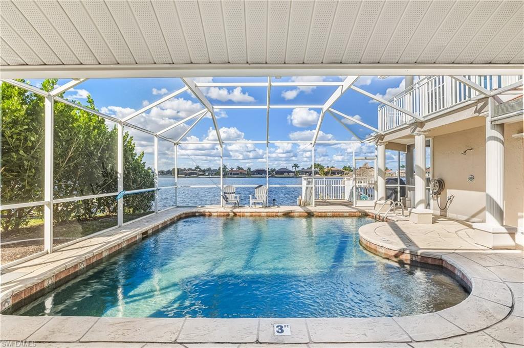 Outdoor pool with glass enclosure, a sunroom, a patio, and a water view