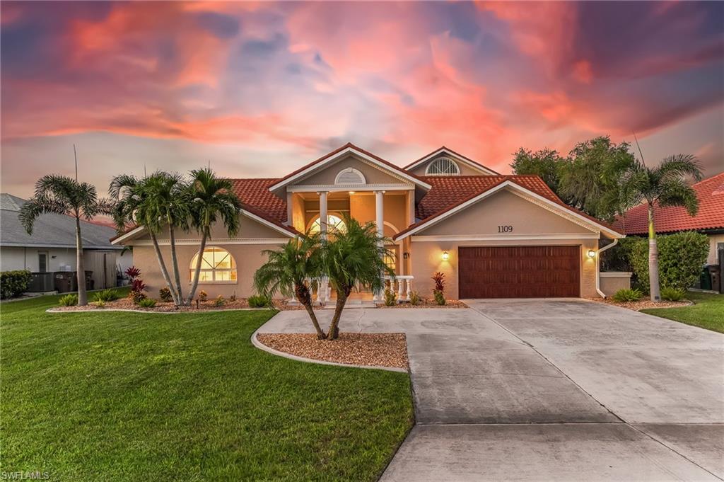 View of front facade with a front lawn, driveway, stucco siding, and a garage