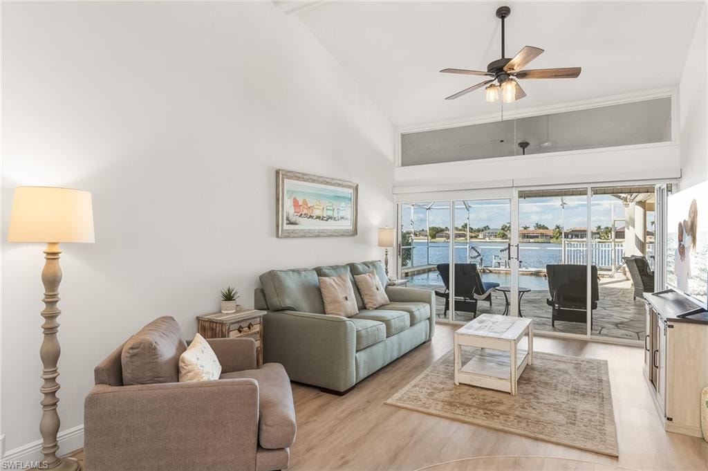 Living room with high vaulted ceiling, light wood-style floors, a ceiling fan, and a sunroom