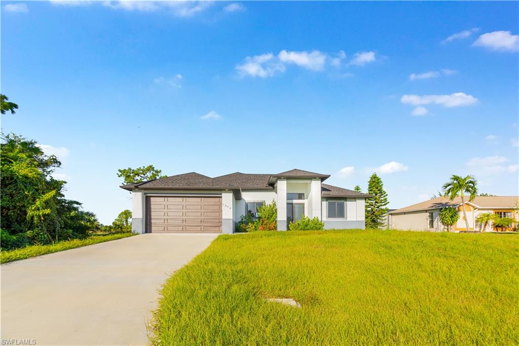 Prairie-style house featuring a front yard, concrete driveway, a garage, and stucco siding