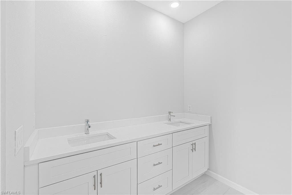Bathroom with double vanity and baseboards