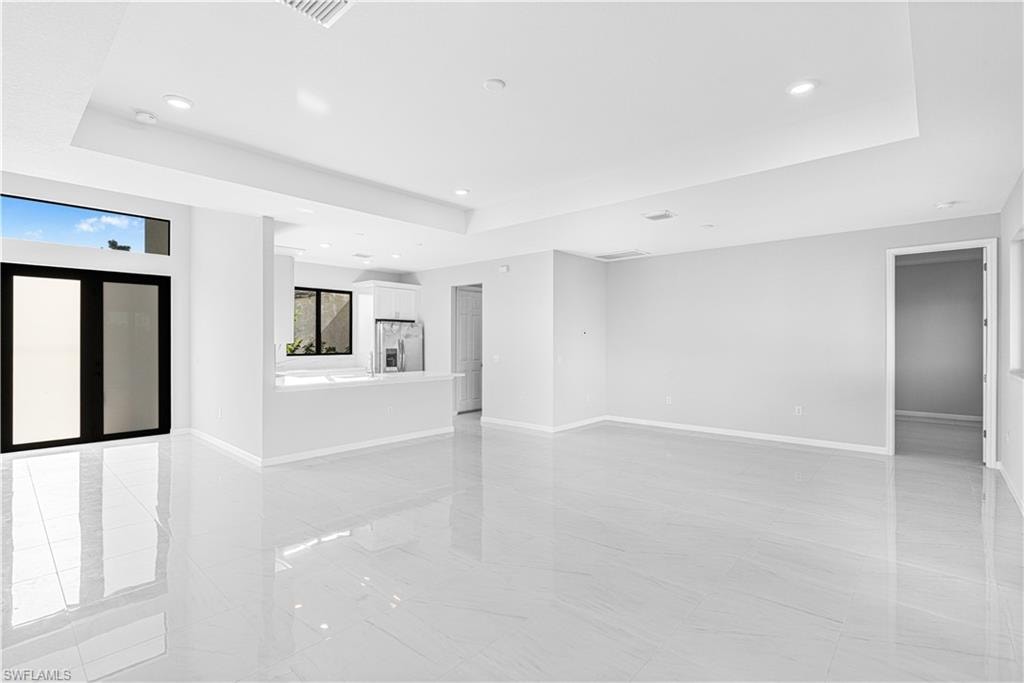 Unfurnished living room with a raised ceiling and recessed lighting