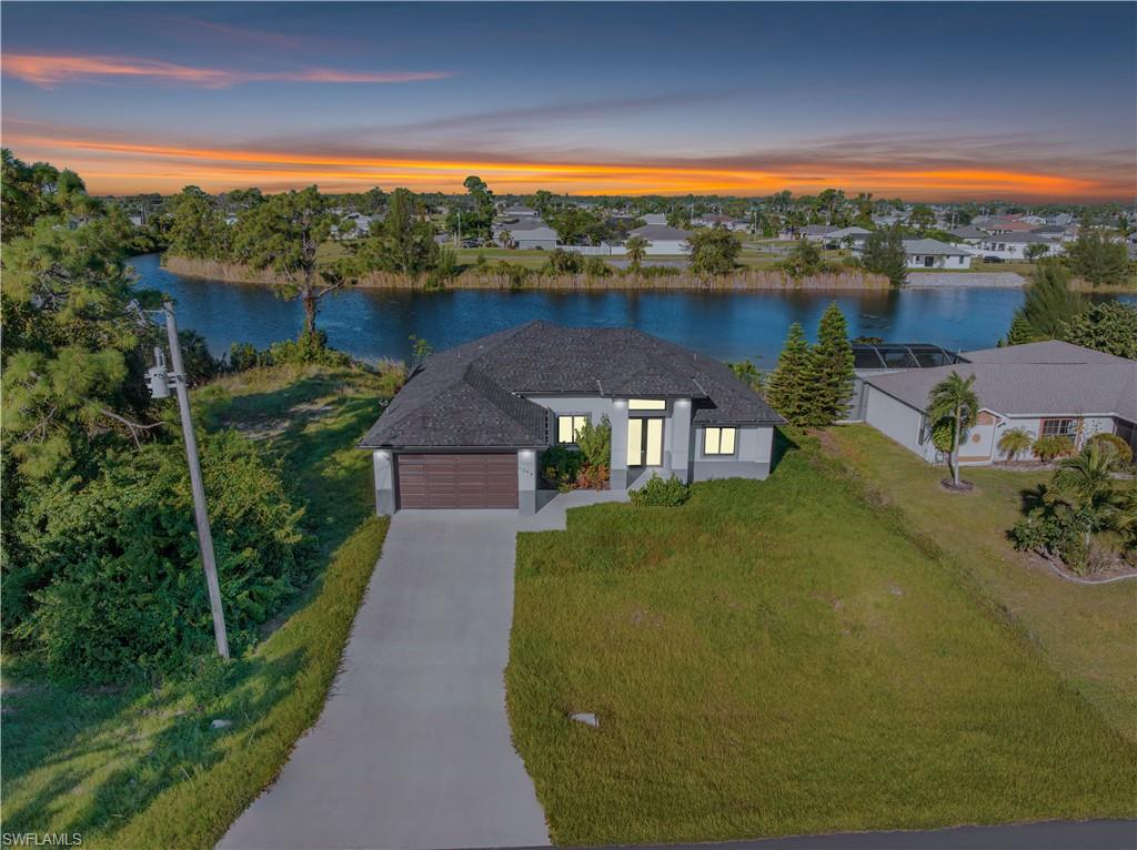 View of front facade with a front yard, a water view, an attached garage, and concrete driveway