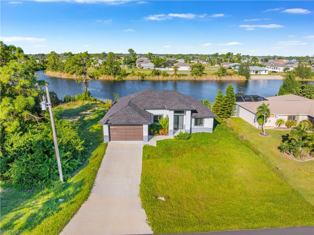Ranch-style home with a front lawn, an attached garage, a water view, driveway, and a residential view