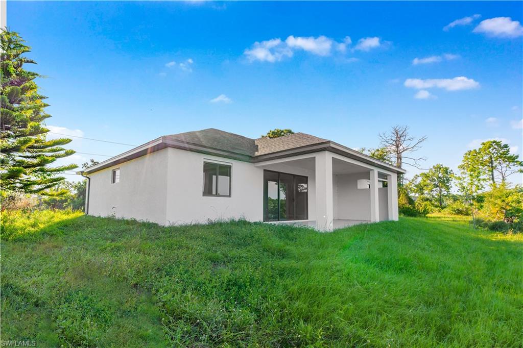 Rear view of property featuring stucco siding, a patio, and a yard