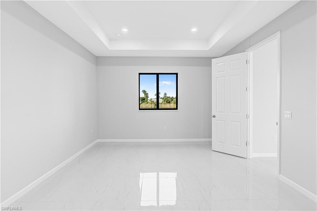 Unfurnished room featuring a raised ceiling and recessed lighting
