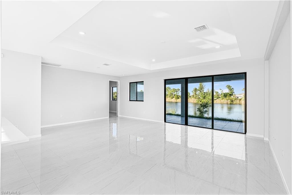 Empty room featuring a tray ceiling, a water view, and recessed lighting