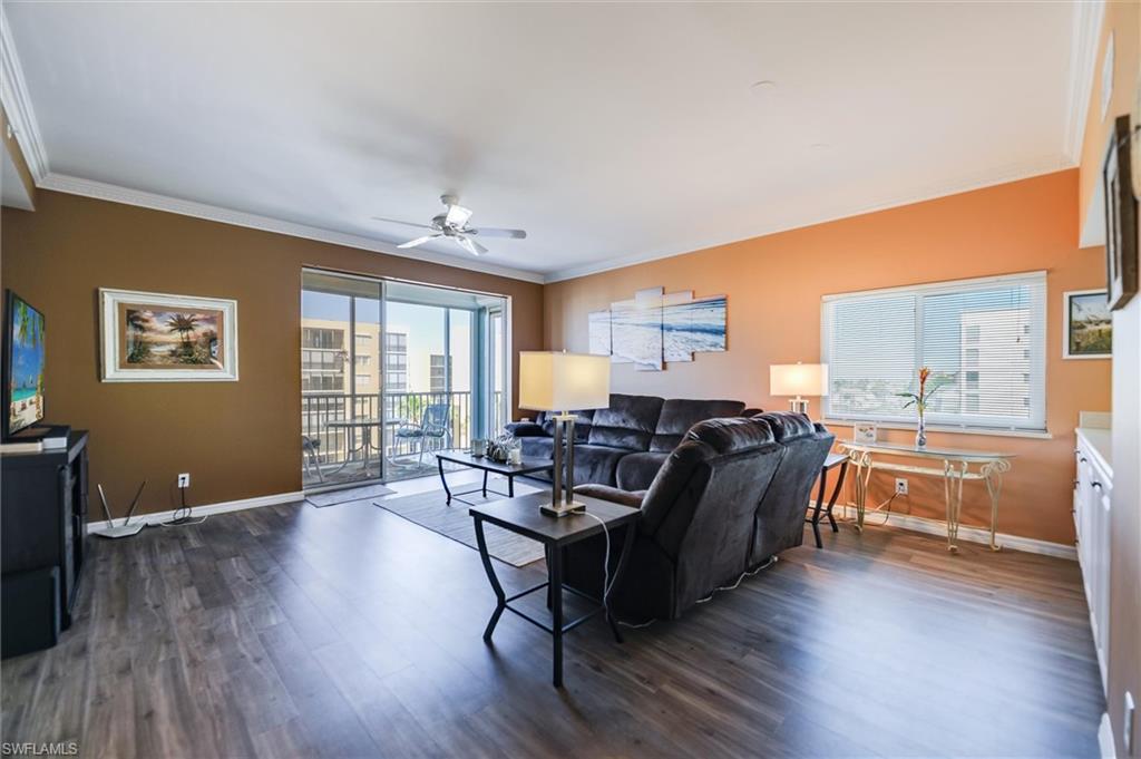 Living room featuring ornamental molding, dark wood-style floors, and ceiling fan