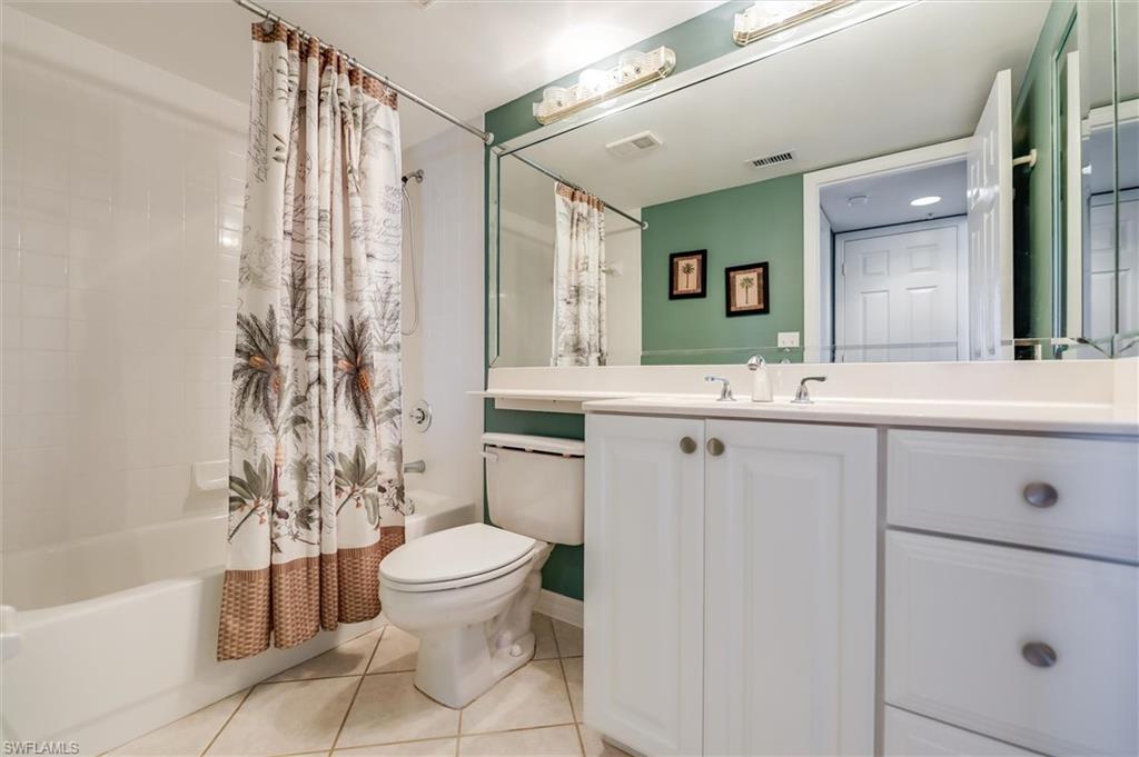 Full bath with light tile patterned floors, shower / bath combo with shower curtain, and vanity