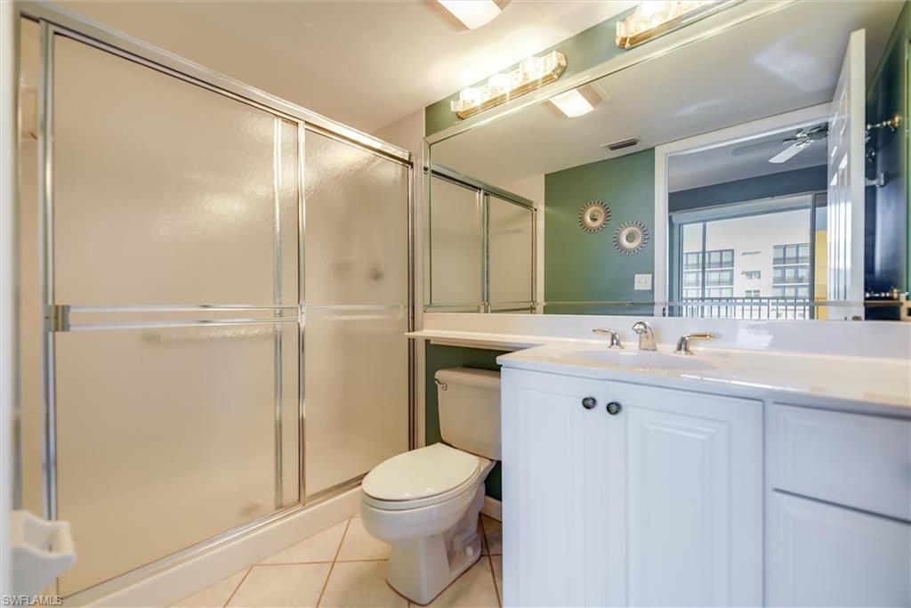 Bathroom featuring light tile patterned flooring, vanity, a stall shower, and ceiling fan