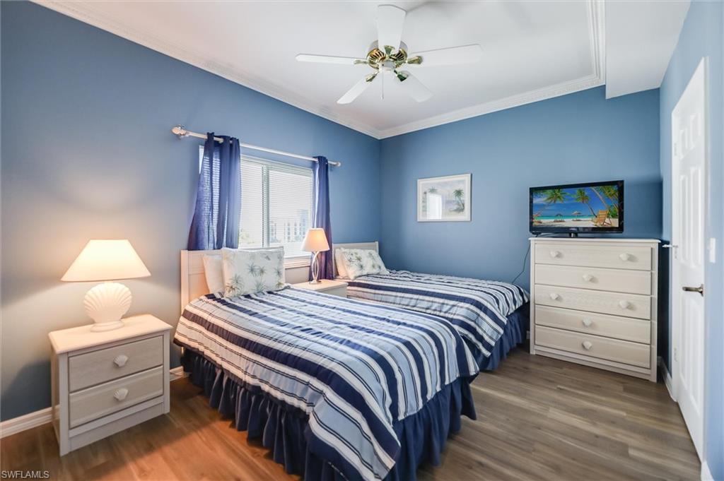 Bedroom with ornamental molding, wood finished floors, and a ceiling fan