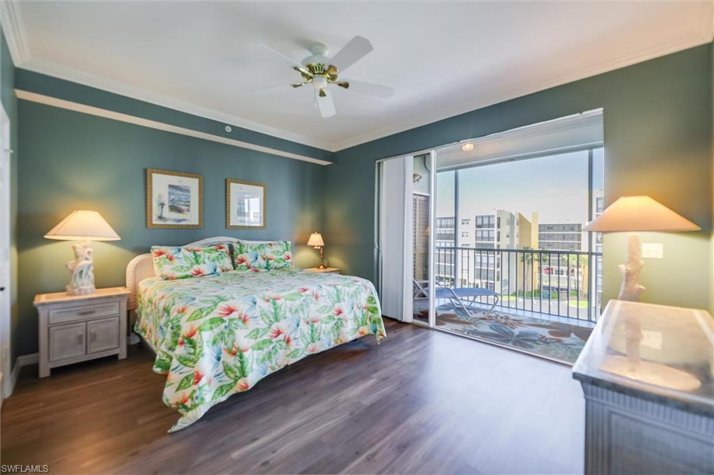 Bedroom featuring access to outside, dark wood-style flooring, crown molding, and a ceiling fan