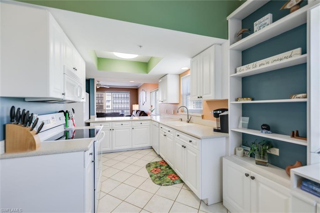 Kitchen with white appliances, open shelves, white cabinetry, and light tile patterned floors