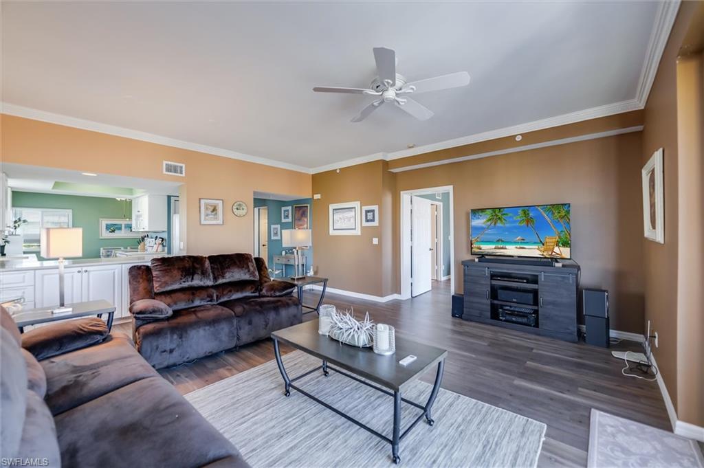 Living room featuring ornamental molding, dark wood-type flooring, and ceiling fan