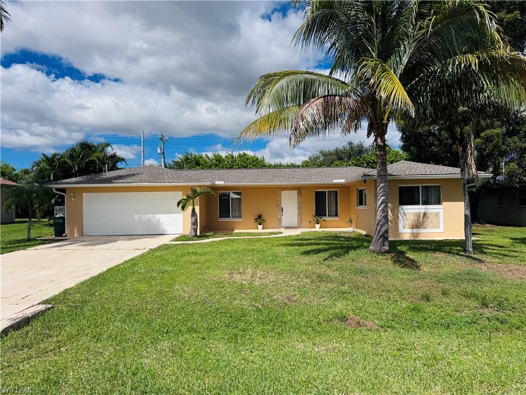 Ranch-style home with stucco siding, driveway, a garage, and a front lawn
