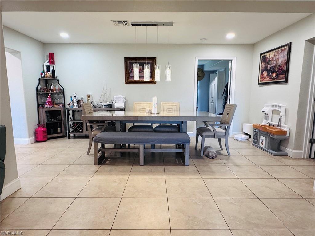 Dining space with light tile patterned floors and recessed lighting