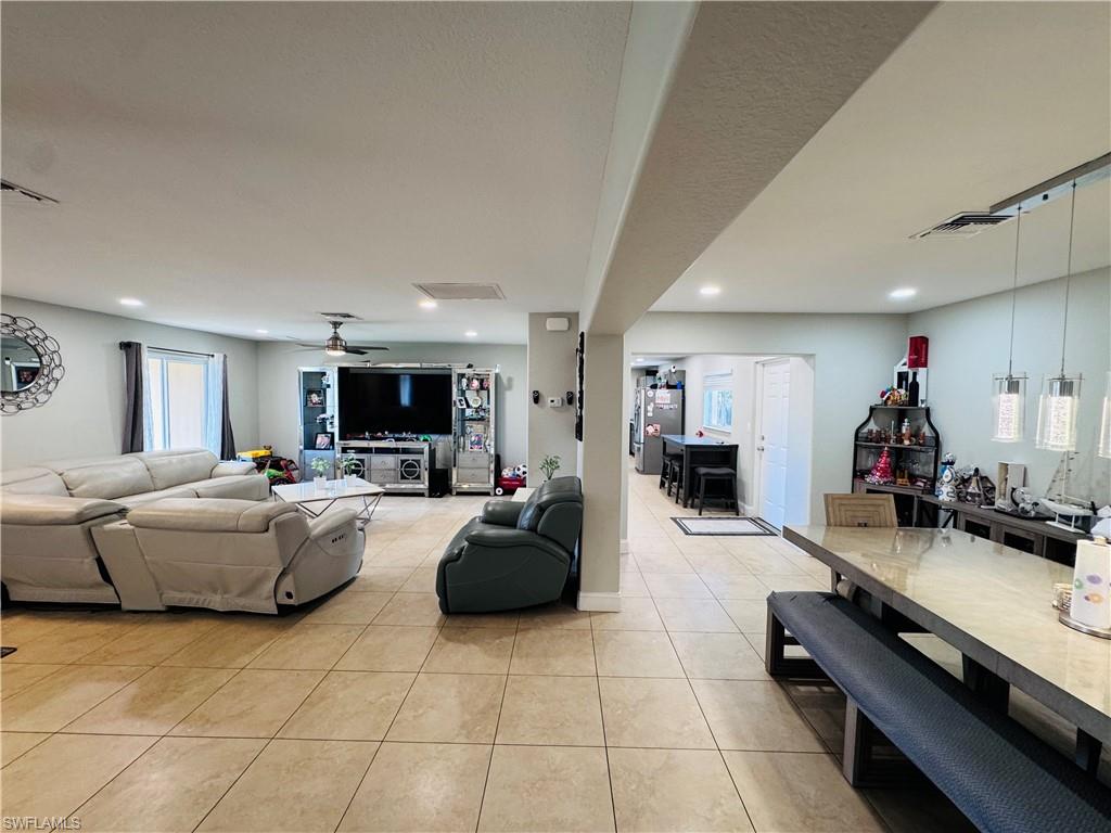 Living room with light tile patterned floors, a ceiling fan, and recessed lighting
