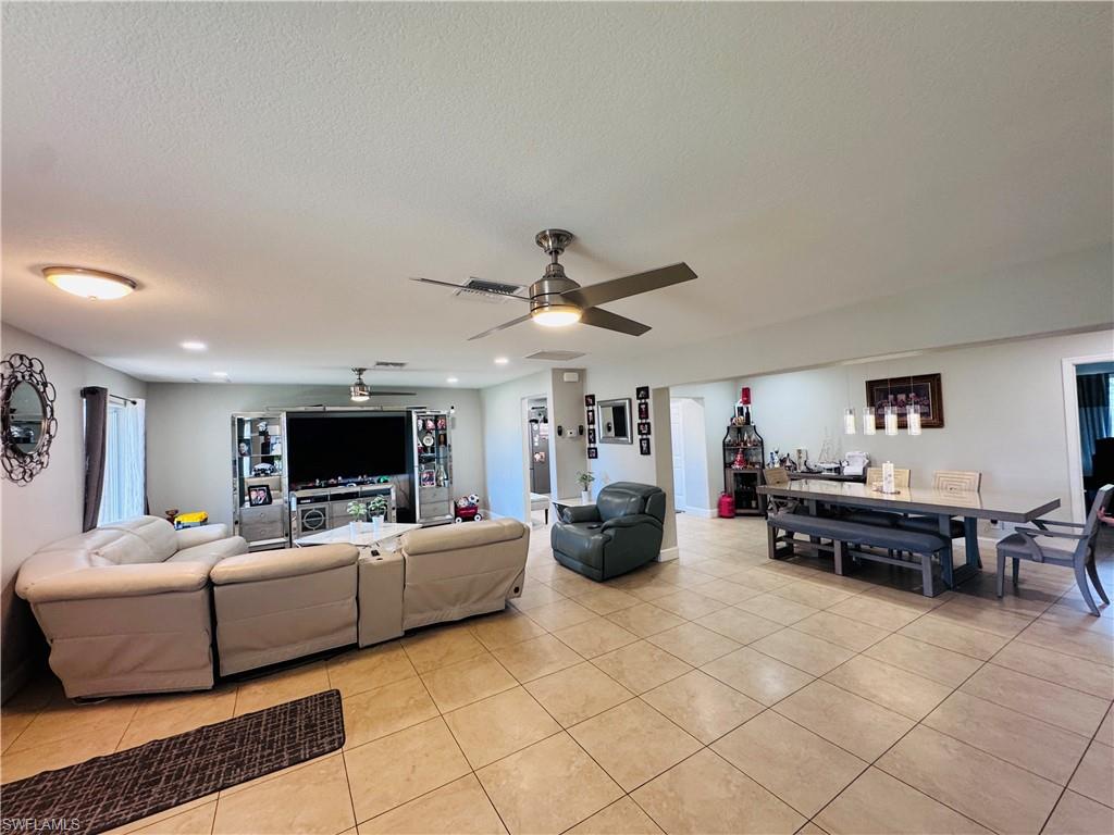 Living room with light tile patterned flooring, ceiling fan, recessed lighting, and a textured ceiling