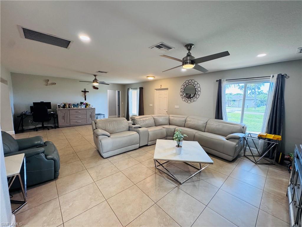 Living room with light tile patterned floors, recessed lighting, built in desk, and a ceiling fan