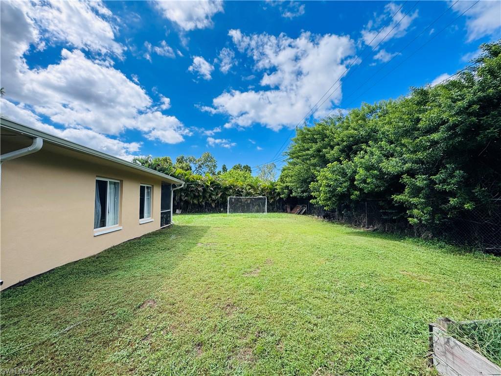 View of grassy yard featuring view of scattered trees and a sunroom