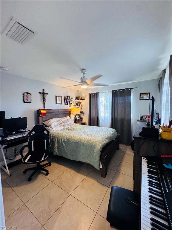 Bedroom with a desk, a ceiling fan, and light tile patterned flooring