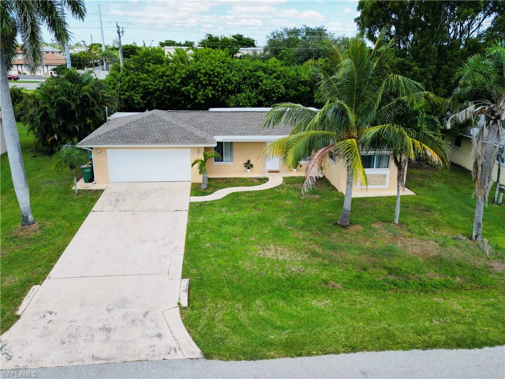 View of front facade featuring stucco siding, concrete driveway, and a front yard