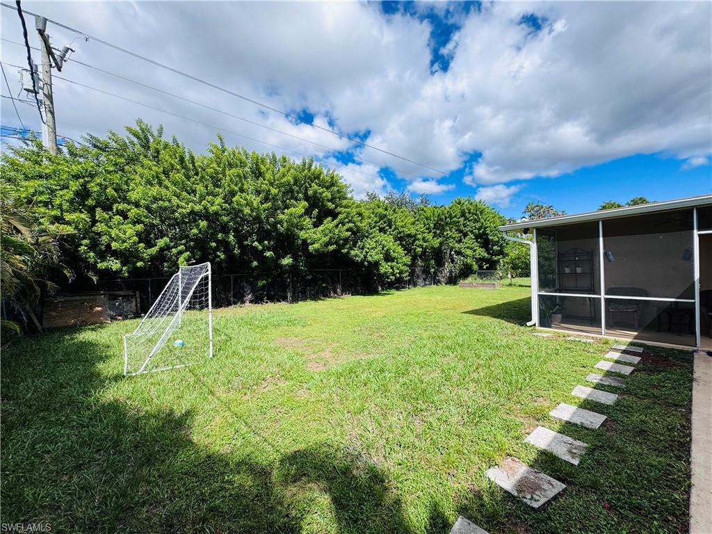 View of yard featuring a sunroom and an area for sports