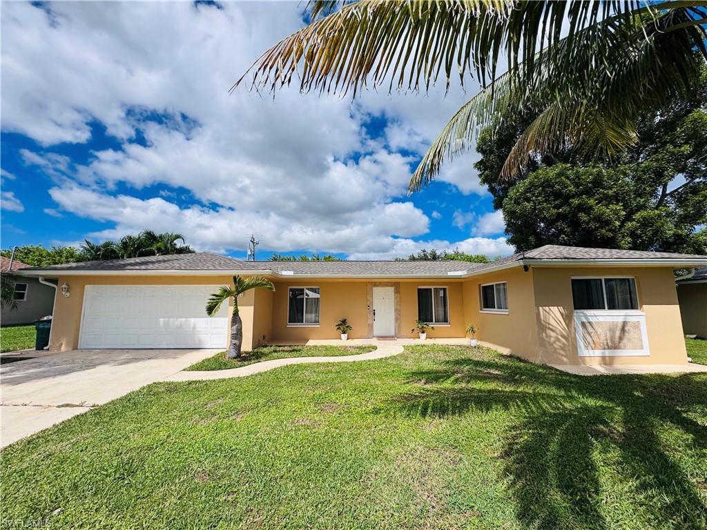 Single story home featuring stucco siding, a front yard, driveway, and an attached garage